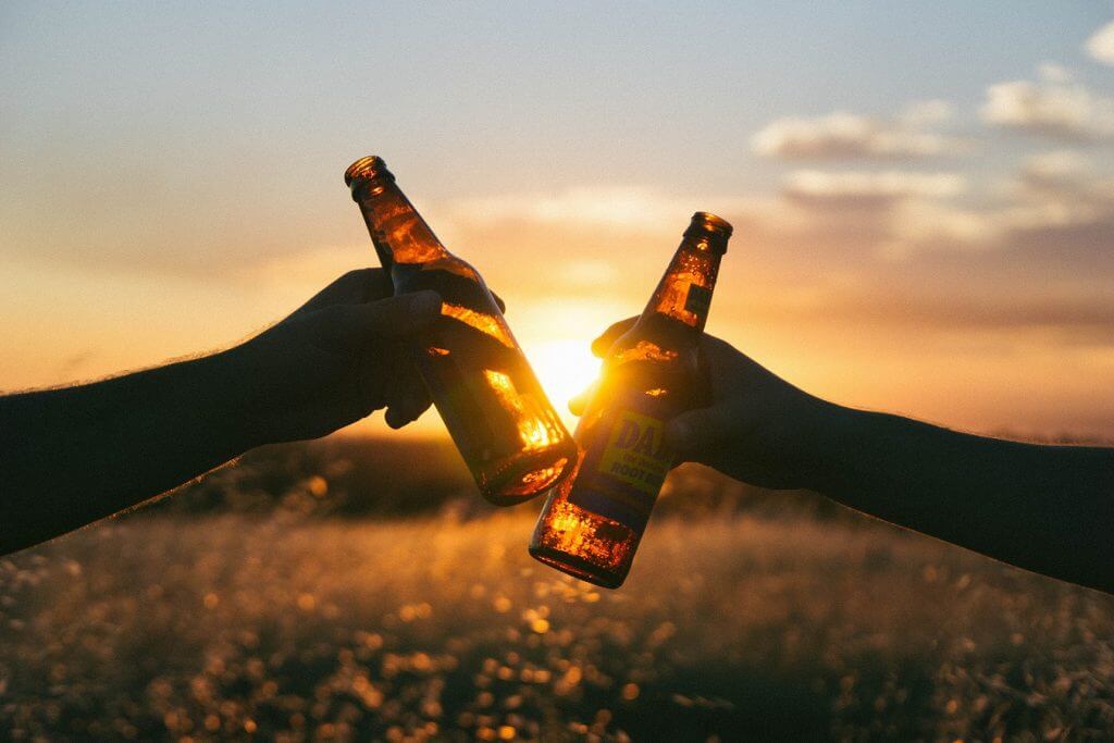 people holding root beer bottles cheersing